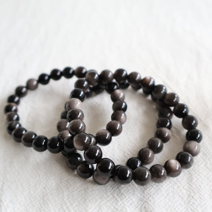 Silver Sheen Obsidian crystal bracelet with polished 8mm round beads on a stretch fit band.