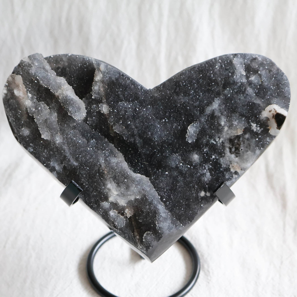 Large Sphalerite druzy crystal heart with dark charcoal-grey sparkling crystal formations displayed on a black metal stand.