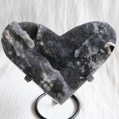 Large Sphalerite druzy crystal heart with dark charcoal-grey sparkling crystal formations displayed on a black metal stand.