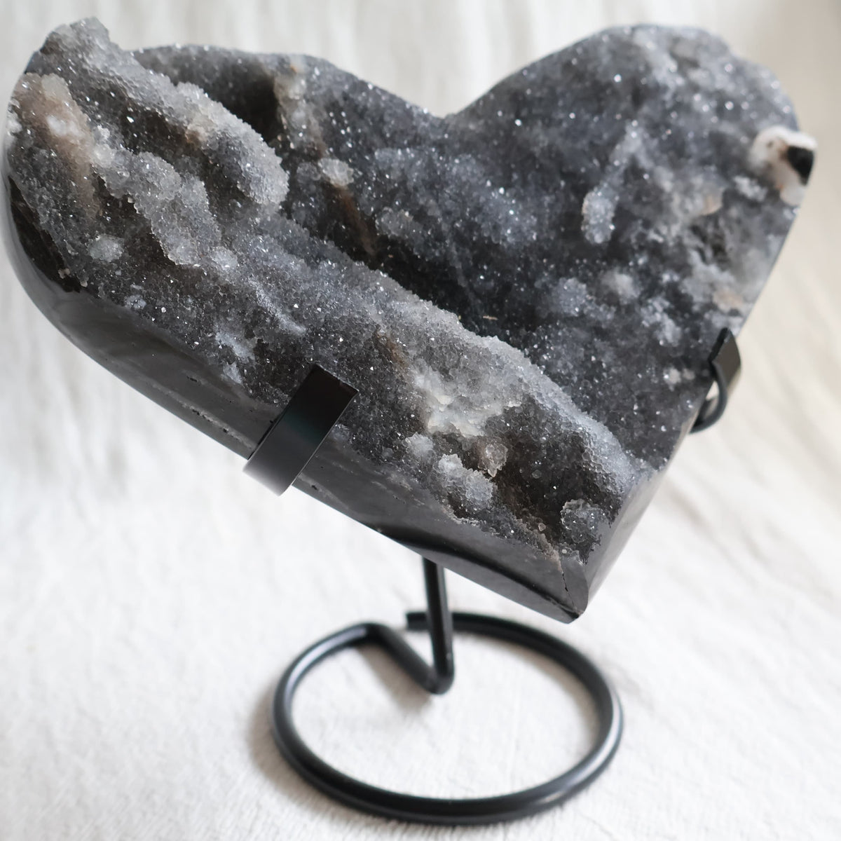 Large Sphalerite druzy crystal heart with dark charcoal-grey sparkling crystal formations displayed on a black metal stand.