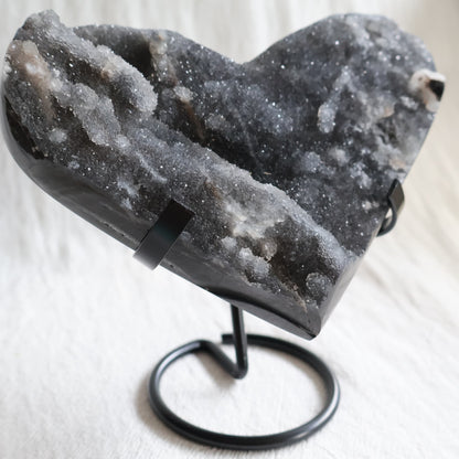 Large Sphalerite druzy crystal heart with dark charcoal-grey sparkling crystal formations displayed on a black metal stand.