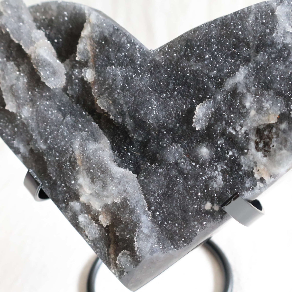 Large Sphalerite druzy crystal heart with dark charcoal-grey sparkling crystal formations displayed on a black metal stand.