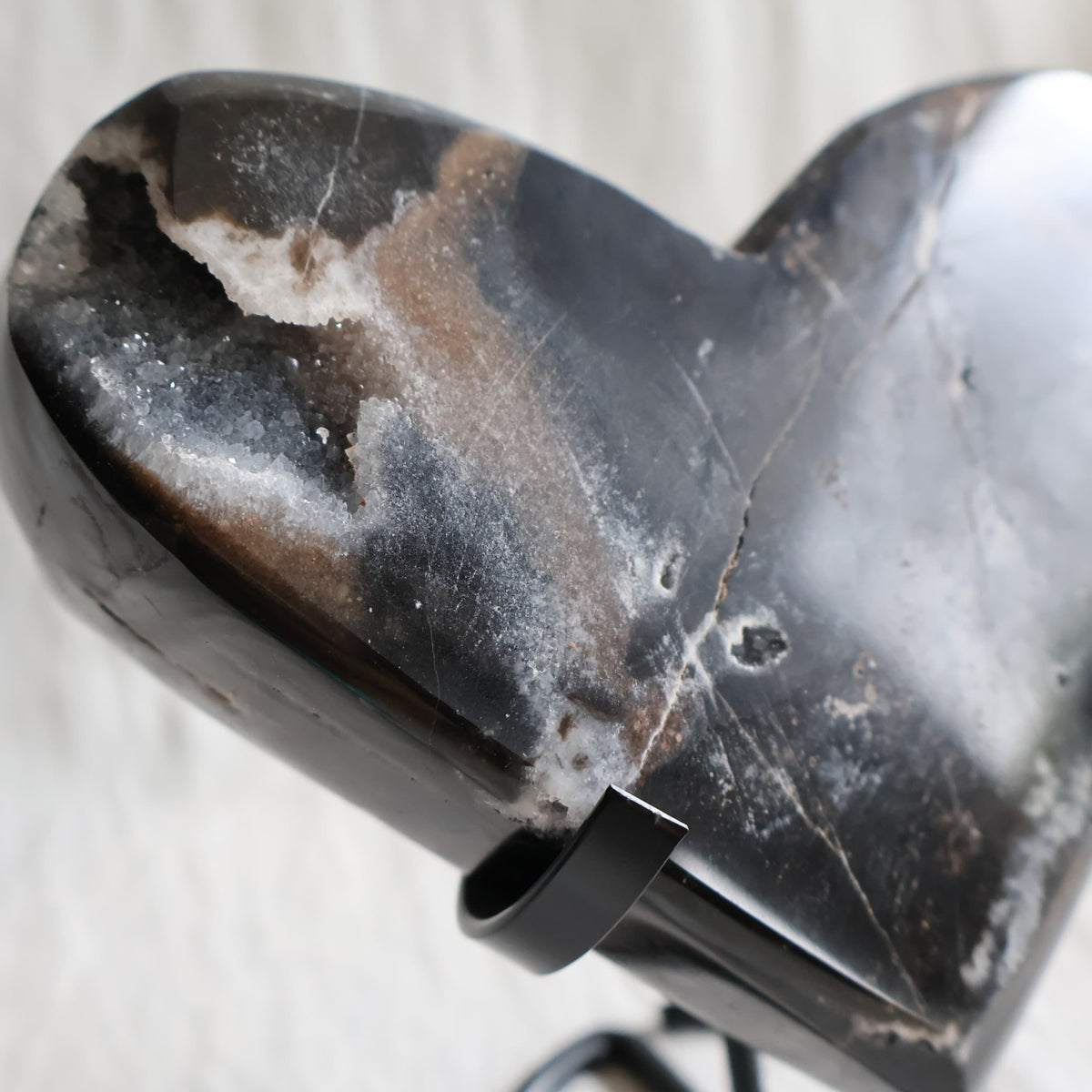 Large Sphalerite druzy crystal heart with dark charcoal-grey sparkling crystal formations displayed on a black metal stand.