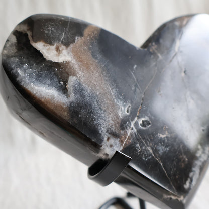 Large Sphalerite druzy crystal heart with dark charcoal-grey sparkling crystal formations displayed on a black metal stand.