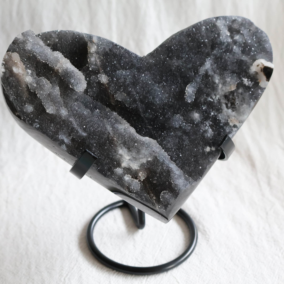 Large Sphalerite druzy crystal heart with dark charcoal-grey sparkling crystal formations displayed on a black metal stand.