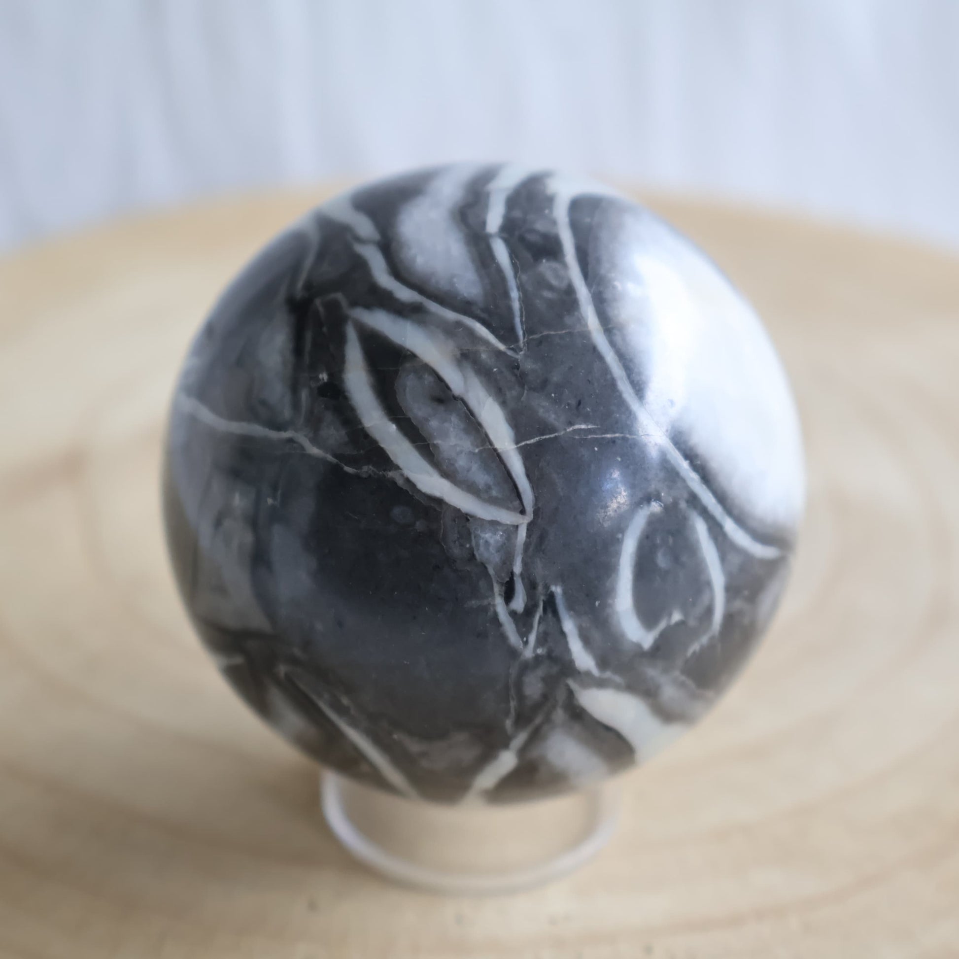Thousand Eye Jasper sphere with swirling black, grey and creamy white fossil patterns and distinctive eye-like formations, 6cm polished sphere
