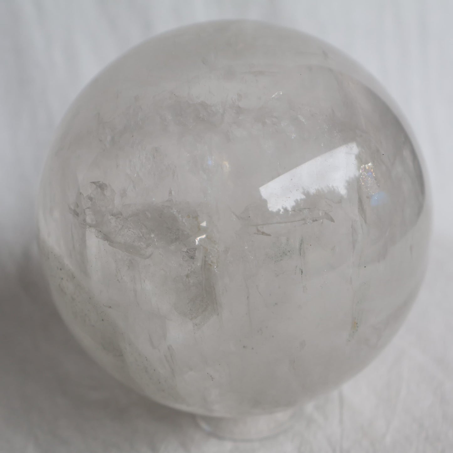 Large White Calcite sphere with soft white colouring, natural inclusions and internal rainbow flashes, 10cm diameter and weighing 1.624kg.