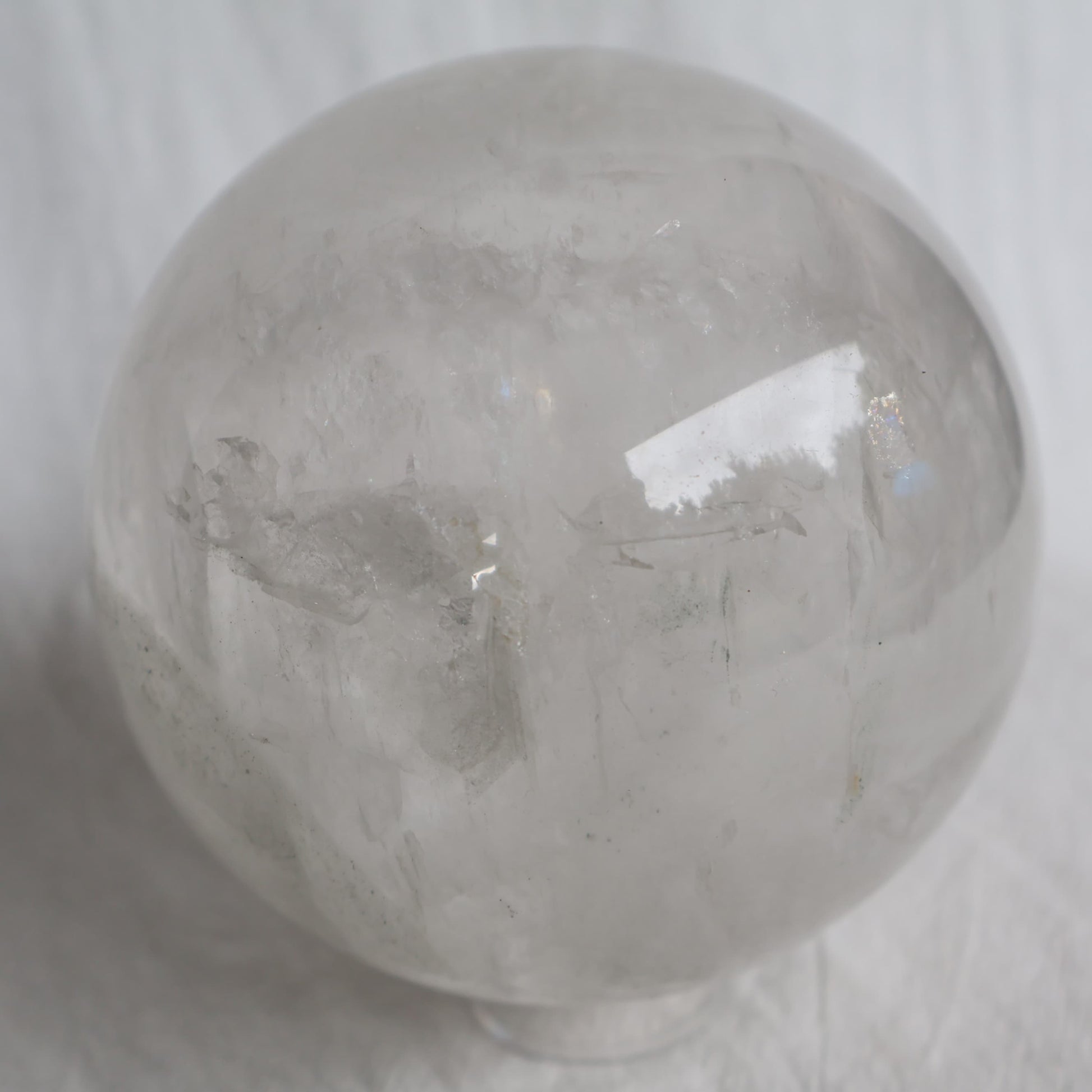 Large White Calcite sphere with soft white colouring, natural inclusions and internal rainbow flashes, 10cm diameter and weighing 1.624kg.