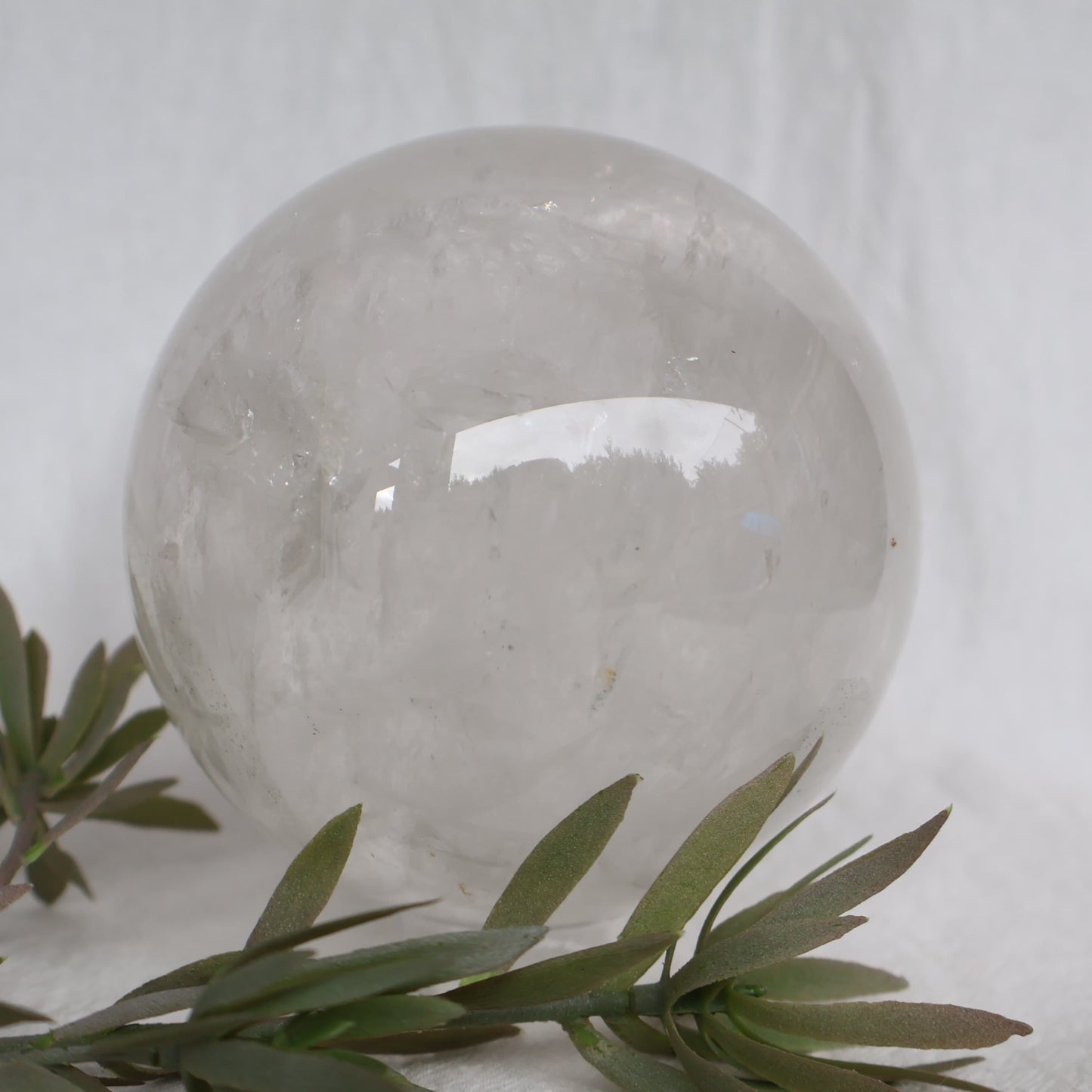 Large White Calcite sphere with soft white colouring, natural inclusions and internal rainbow flashes, 10cm diameter and weighing 1.624kg.