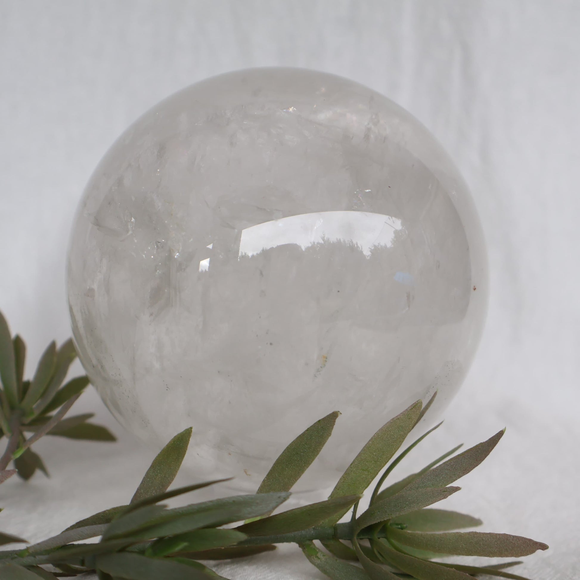 Large White Calcite sphere with soft white colouring, natural inclusions and internal rainbow flashes, 10cm diameter and weighing 1.624kg.