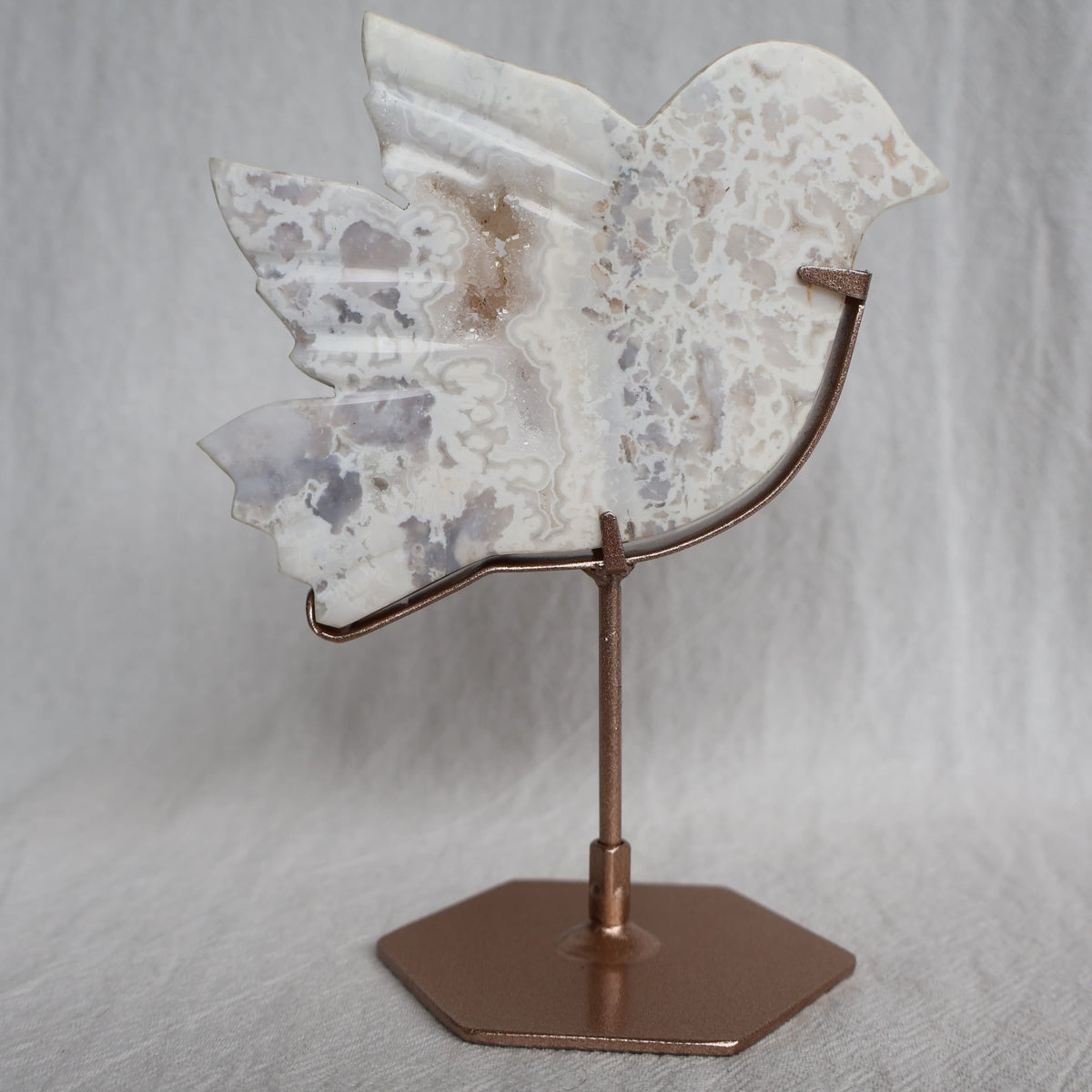 White Plume Agate bird carving on metallic rose gold stand with soft translucent tones and delicate feather-like inclusions, 13.5cm tall.