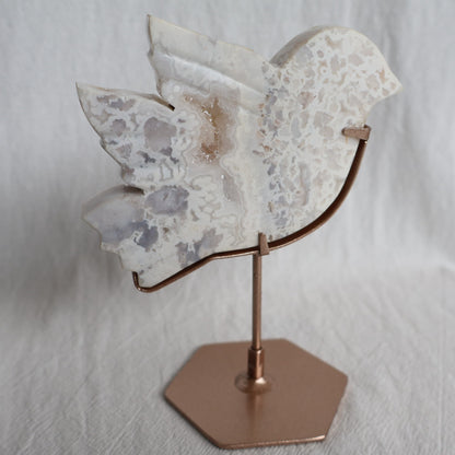 White Plume Agate bird carving on metallic rose gold stand with soft translucent tones and delicate feather-like inclusions, 13.5cm tall.