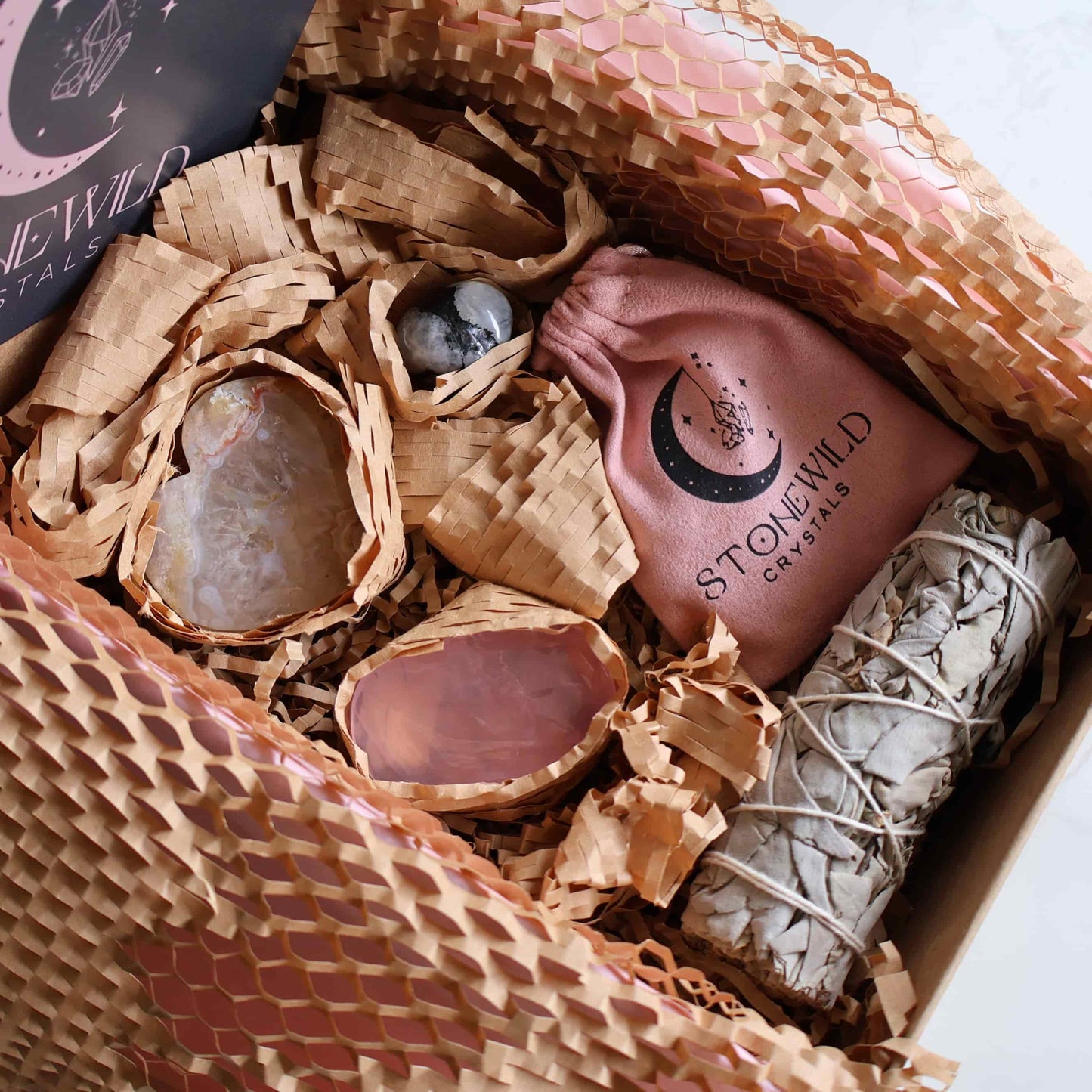 Gift Wrapped - With Love Valentine’s Ritual Set gift box including Flower Agate heart on stand, Rainbow Moonstone bracelet and tumble, Rose Quartz palm stone, and sage bundle