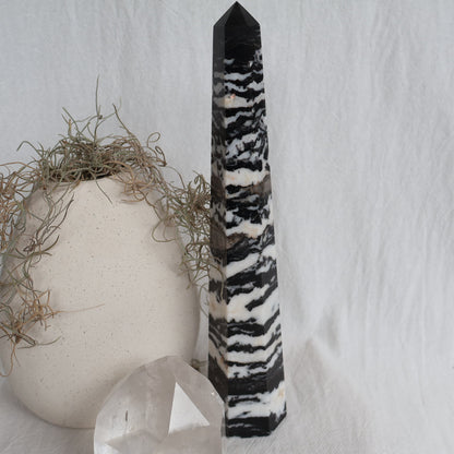 Large Zebra Jasper six-sided obelisk tower with bold natural black, white and grey patterning, standing 25cm tall and weighing 619g.